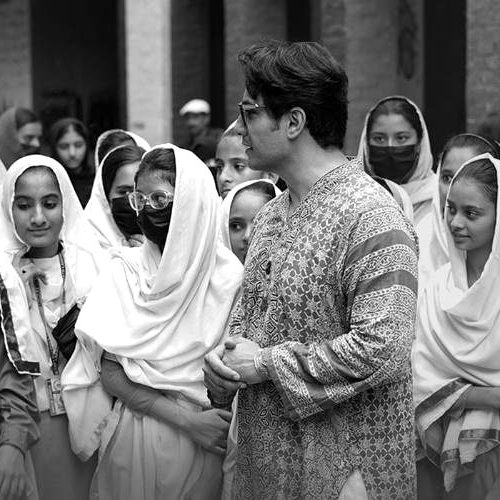 Ali Zafar walking with students at a Foundation school